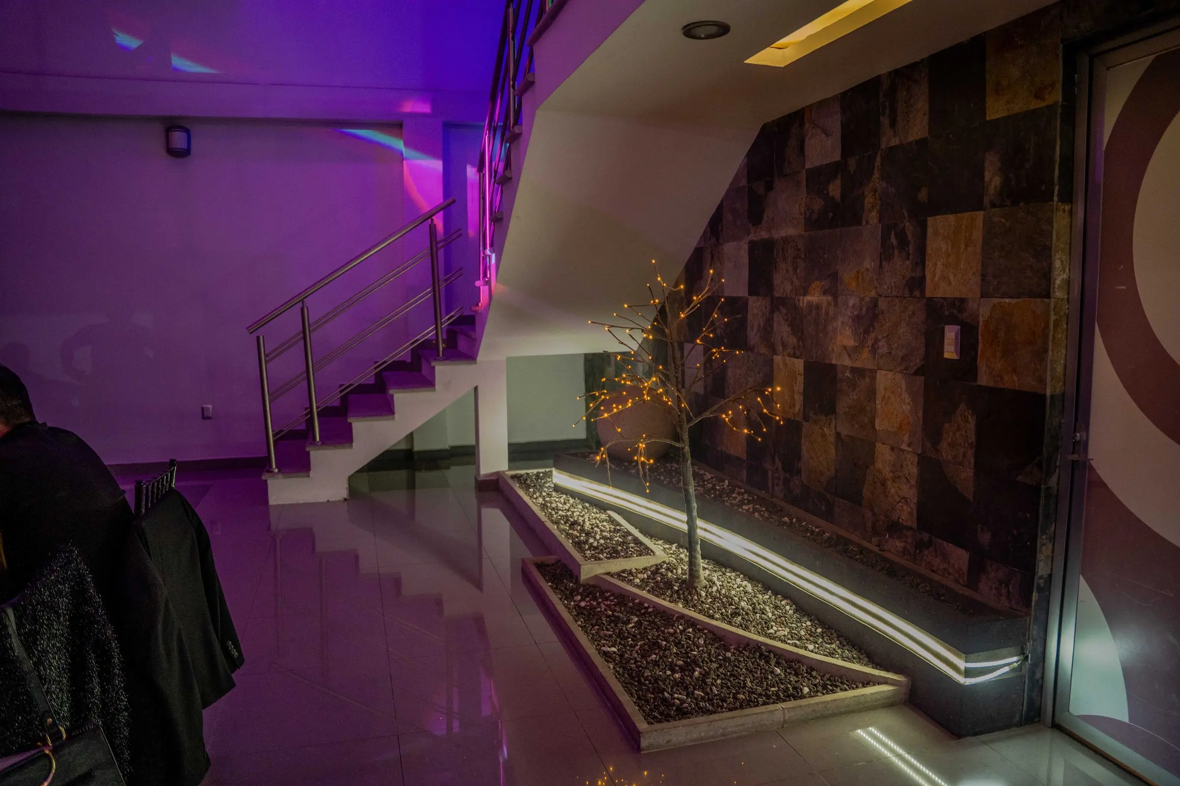 La escalinata junto al muro de piedra, con su jardinera iluminada
