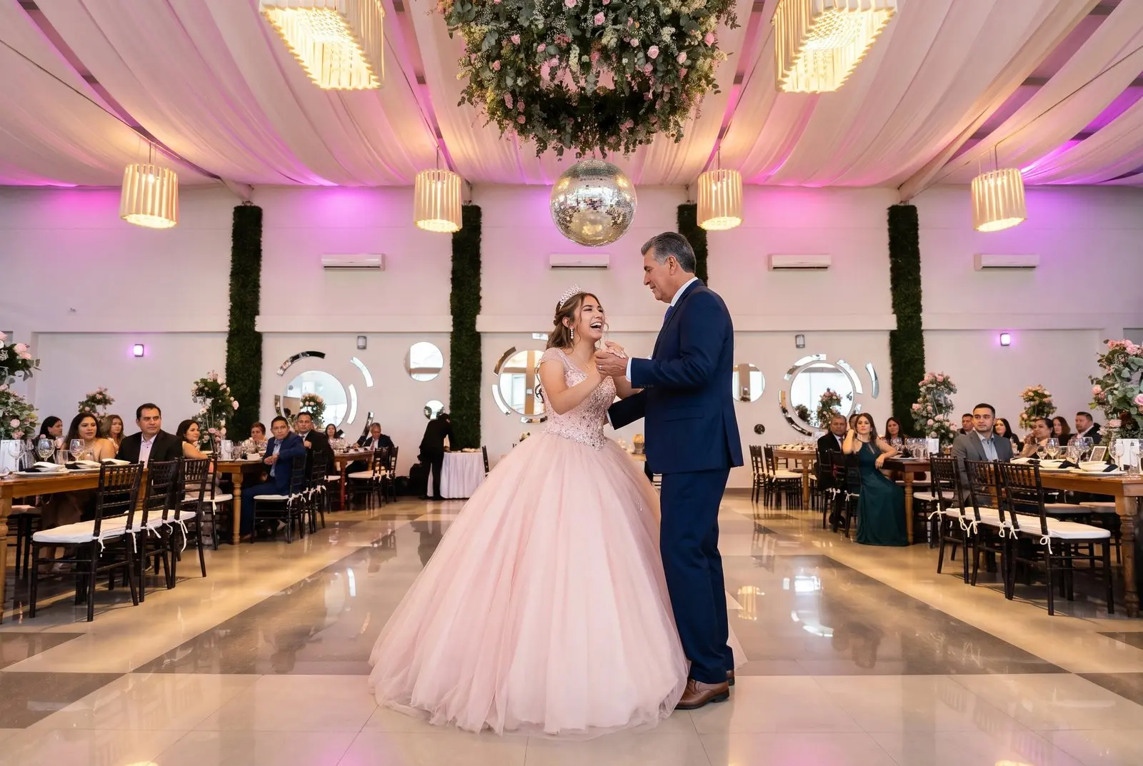 Una quinceañera baila el vals con su papá en la pista del salón