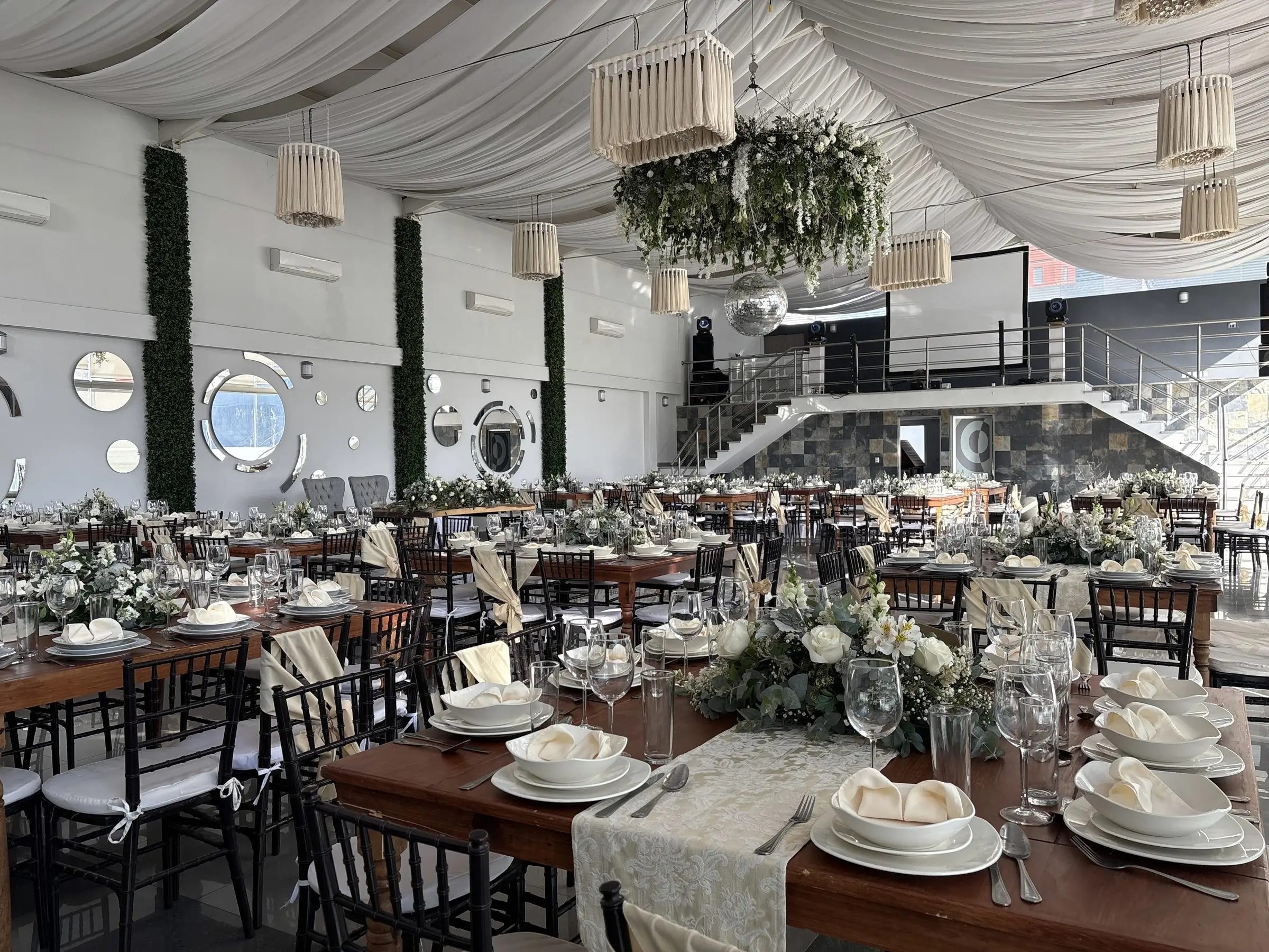 Mesa de madera montada con servilletas y cristalería, con la corona floral al fondo