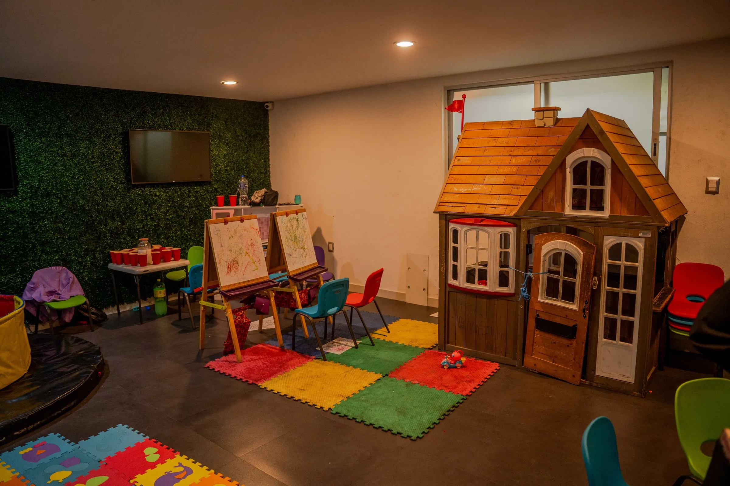 El cuarto de los niños, con una casita de madera, caballetes y tapetes de colores