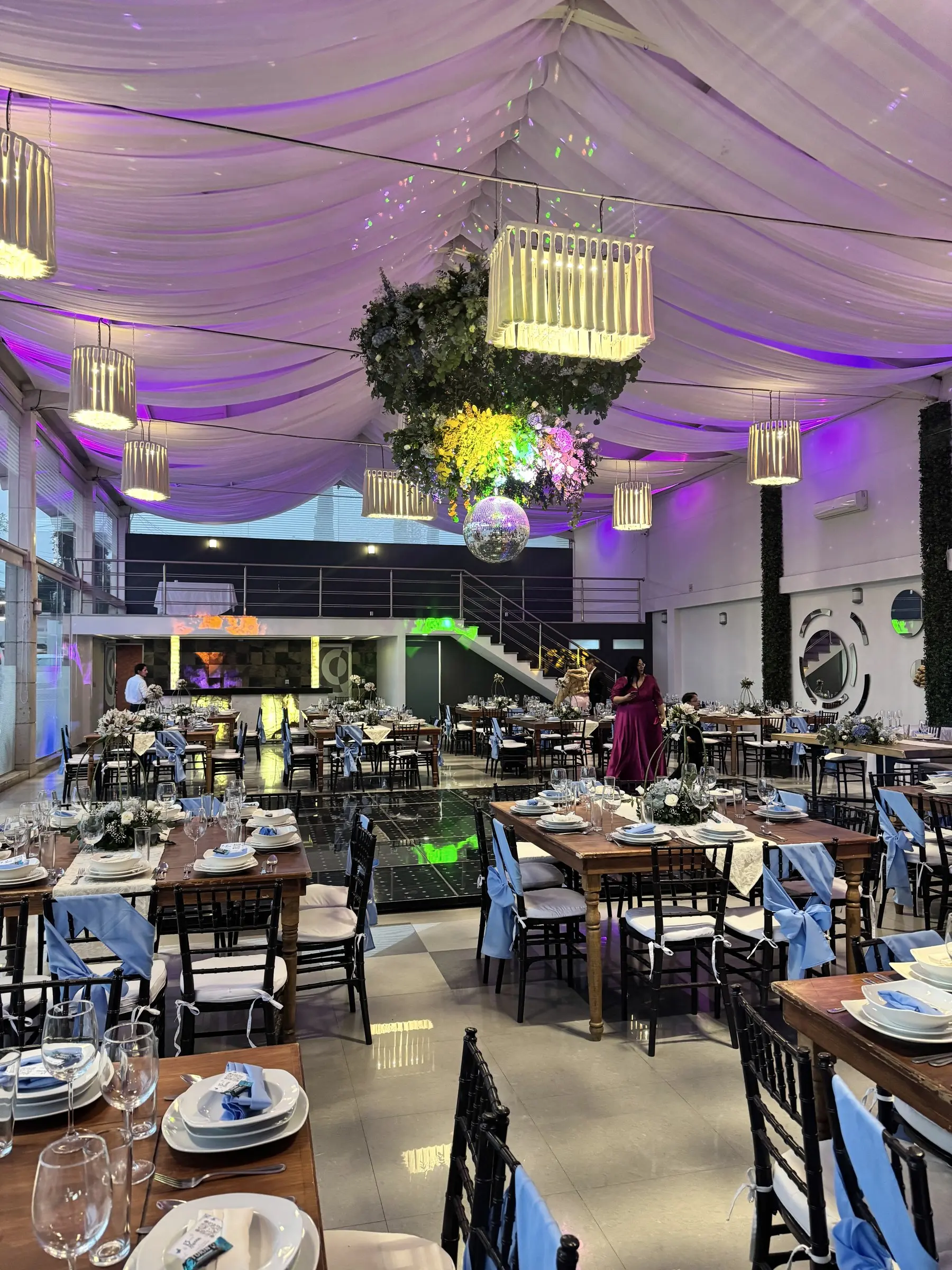 El salón de noche con la escalera y el mezzanine al fondo y la pista de luces