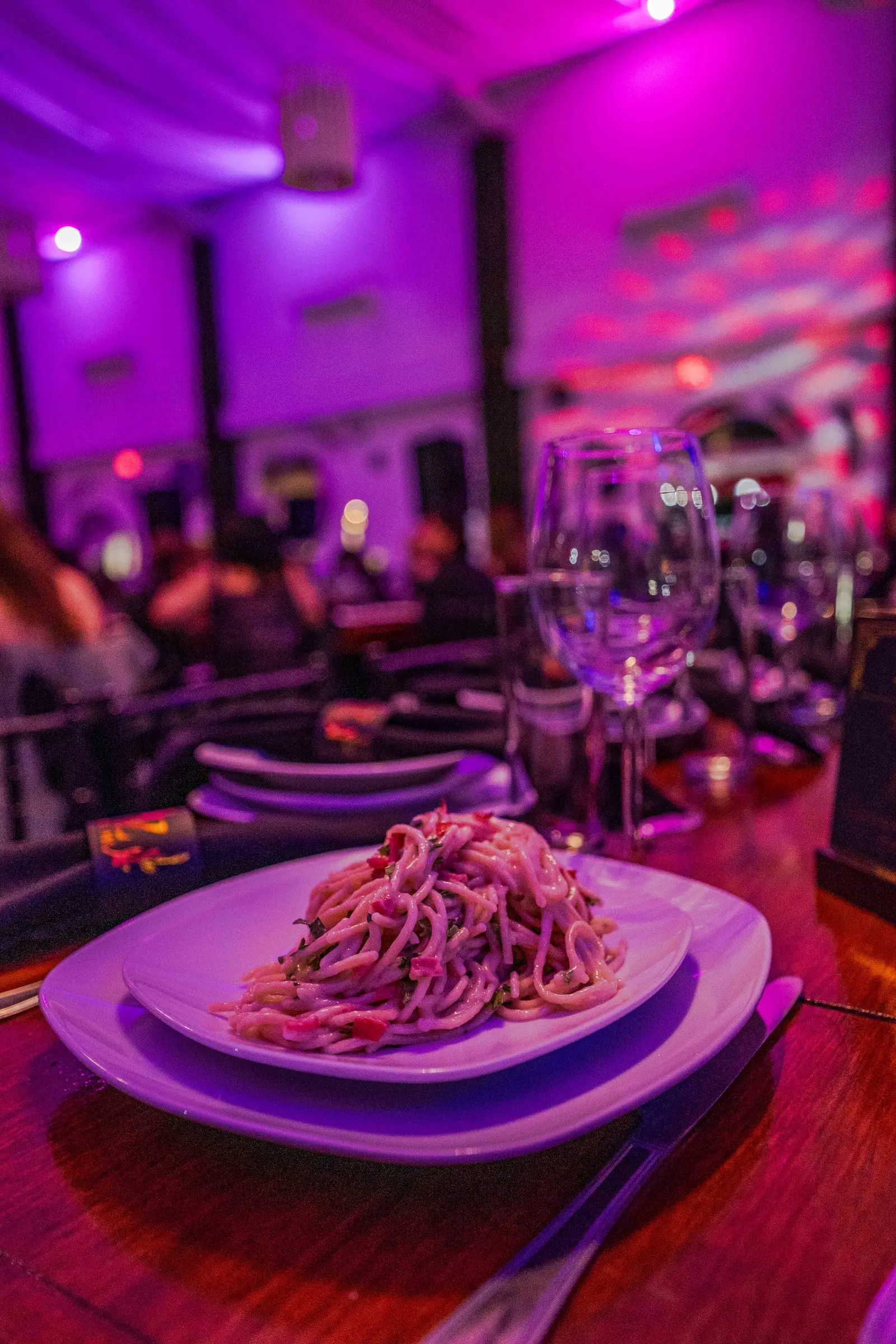 Un plato de pasta servido en la mesa, con el salón iluminado al fondo